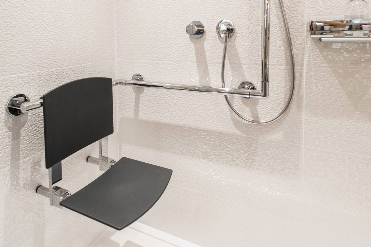 Accessible bathroom - a fold up seat within a shower with handrail