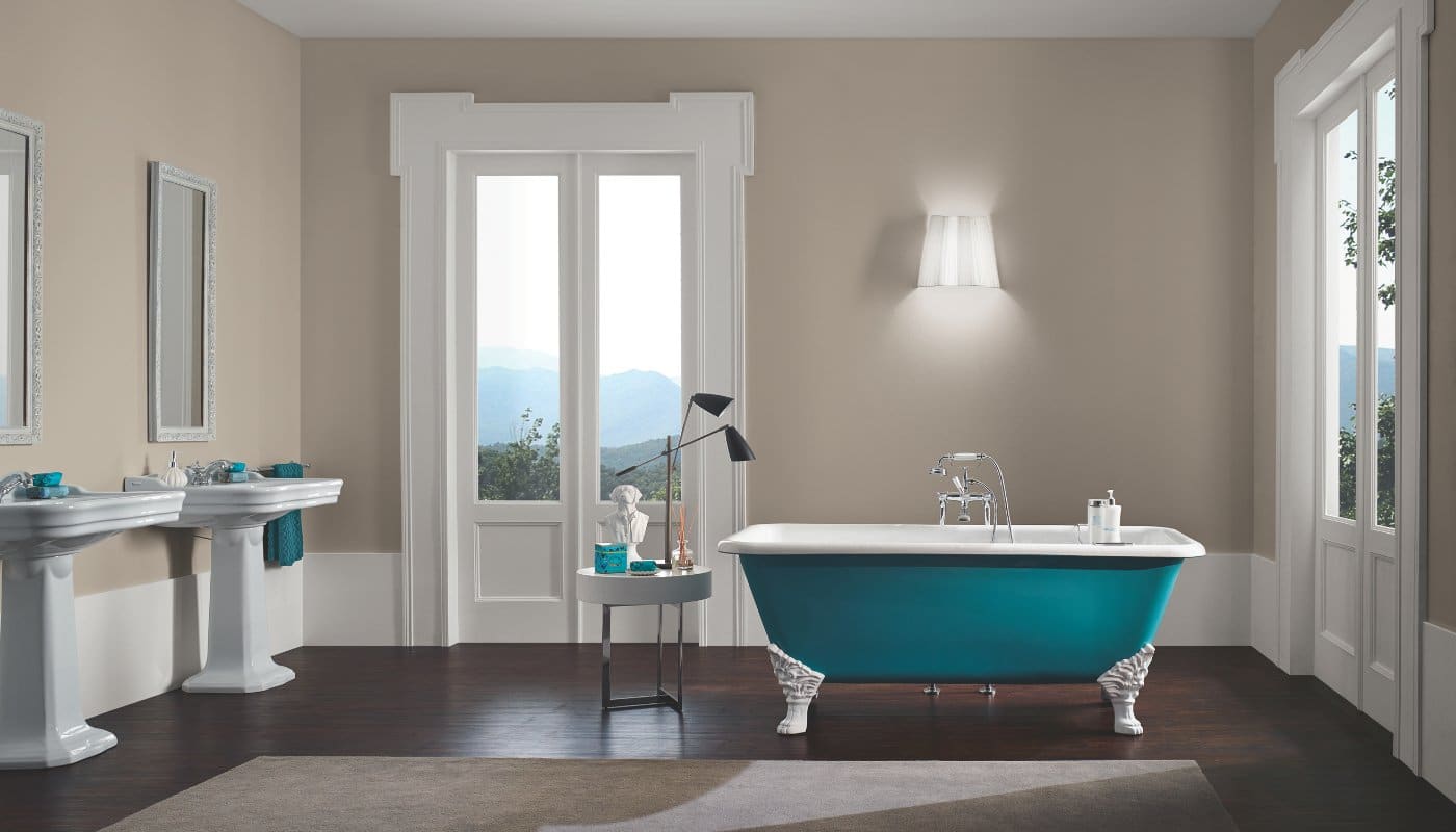 This spacious bathroom displays products from Imperial Bathrooms. It has a large clawfoot bath with a floor-mounted tap, two pedestal sinks, and two mirrors above.