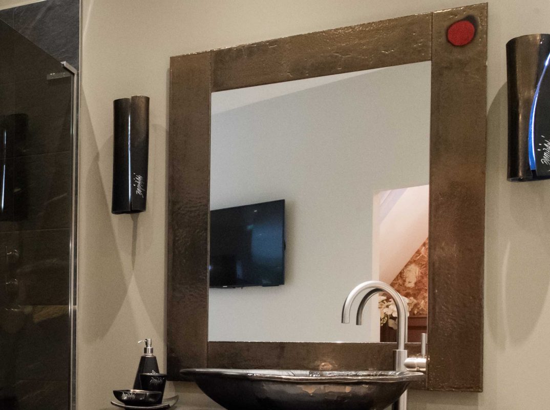 A square wall mounted mirror with a bowl and tap