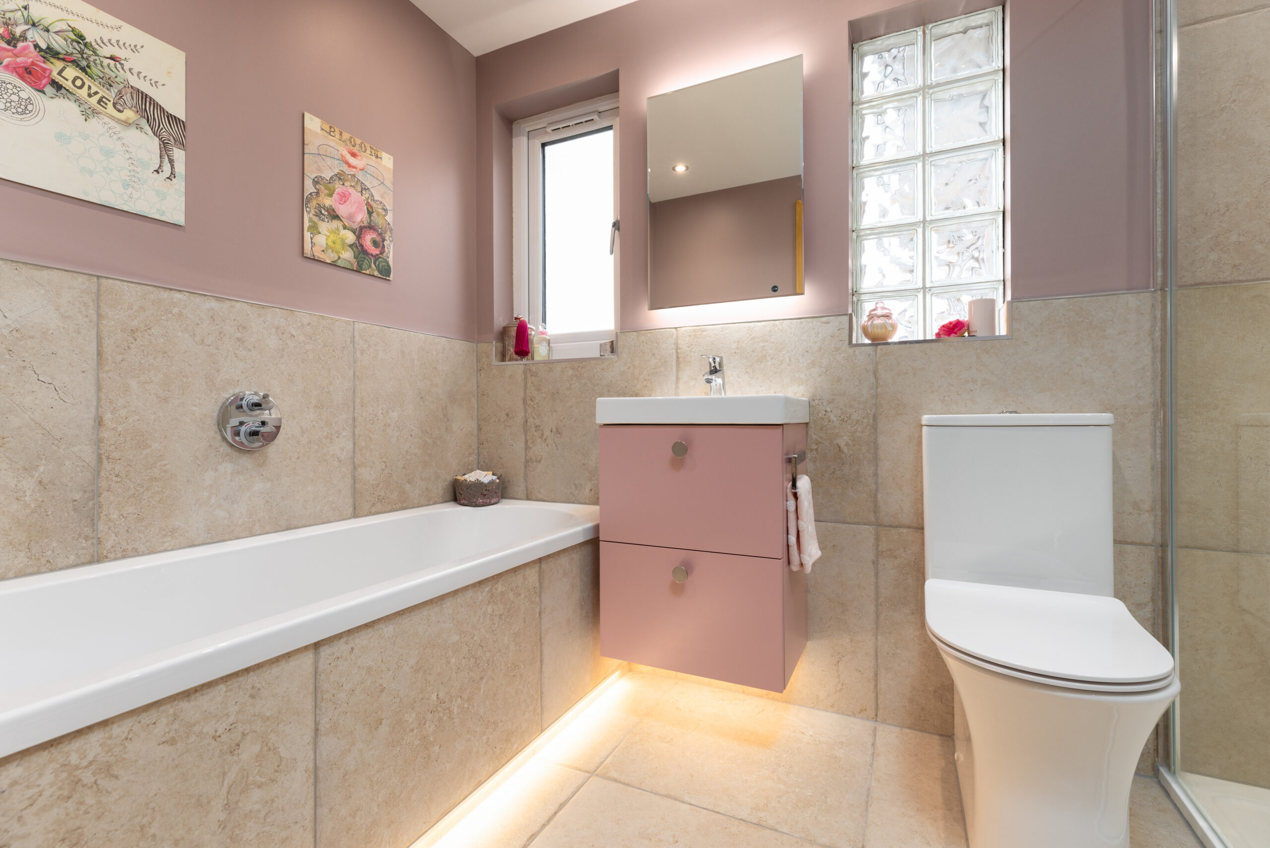 A bathroom renovation in Dundee showing a two-drawer vanity unit in pink colour, WC, and a bath