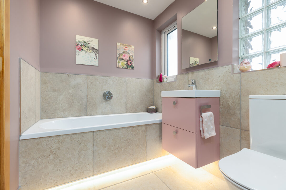 A built-in bath, with a wall-mounted vanity in pink colour, in a newly renovated bathroom in Dundee.