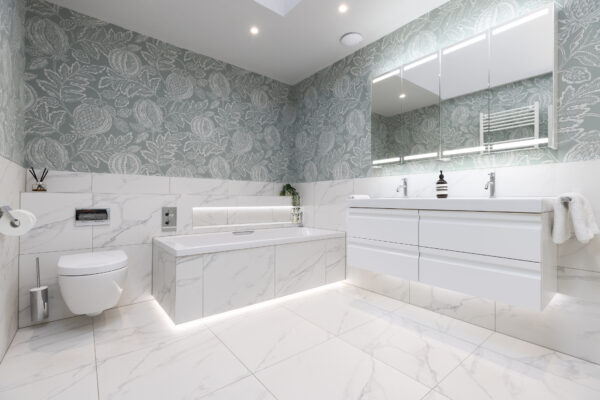 A modern bespoke bathroom renovation in Edinburgh featuring mirror cabinets, bath area, and vanity unit.