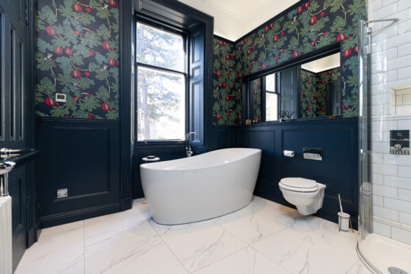 A bathroom renovation carried out by The Bathroom Company. Freestanding bath with a floor-mounted bath mixer on a tiled floor, with a wall-hung WC on the side.