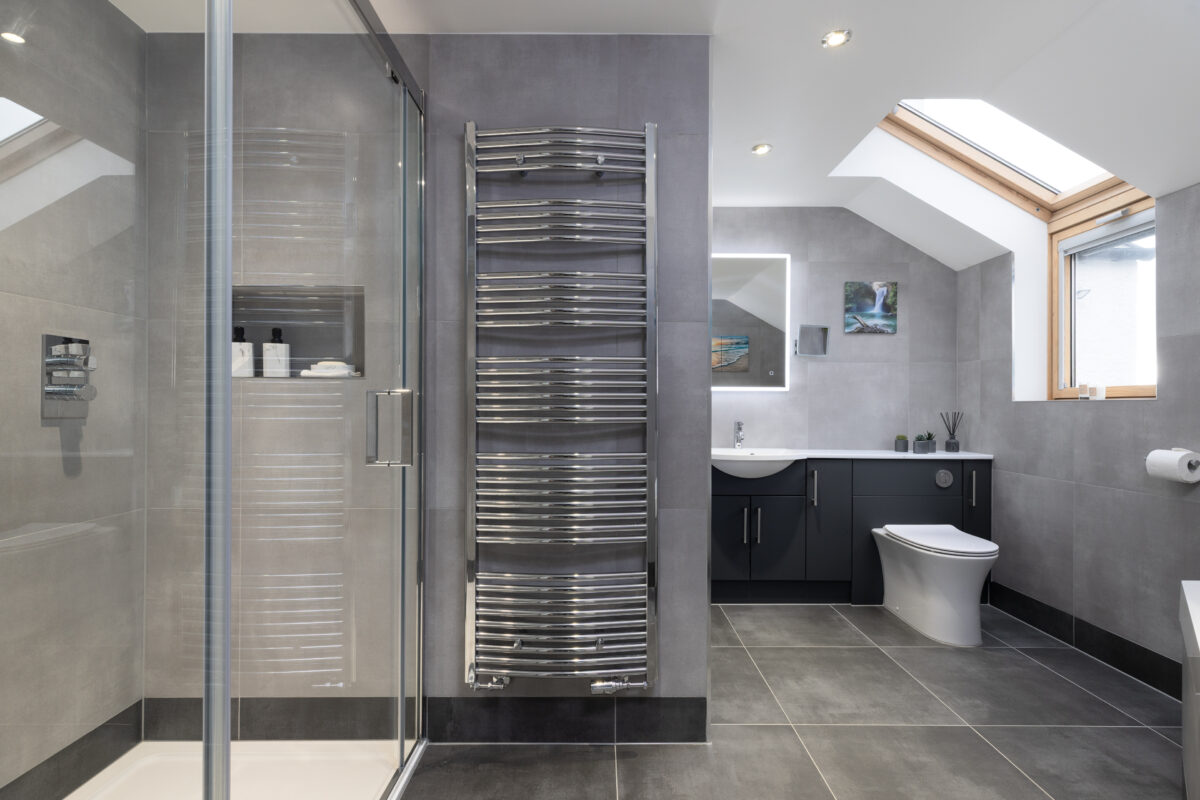 A fully installed modern bathroom in Perthshire features a chrome towel rail, a large shower area, and fitted furniture with a WC.