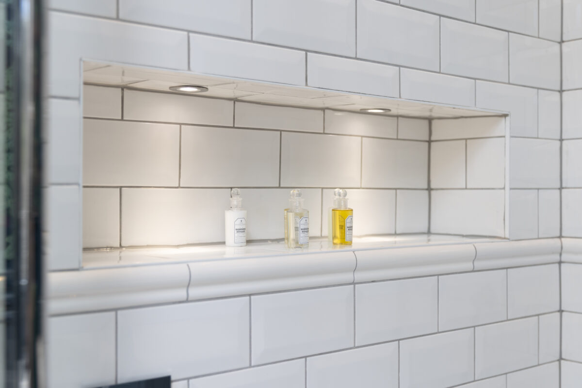 A nicely tiled traditional bathroom style with a recess shelve.