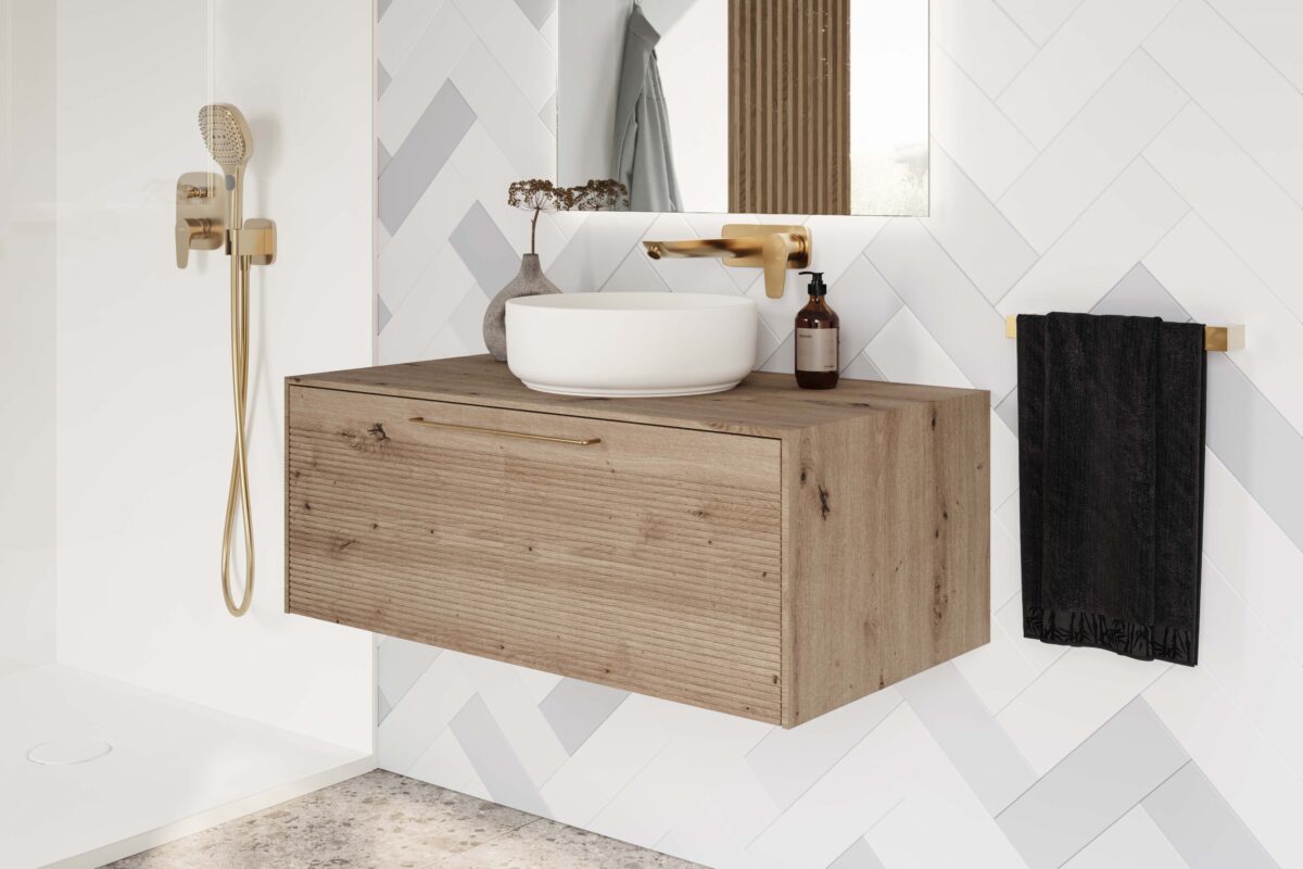 A large wall-mounted vanity with a basin on top. A mixer in brushed brass finish with a shower area beside it.