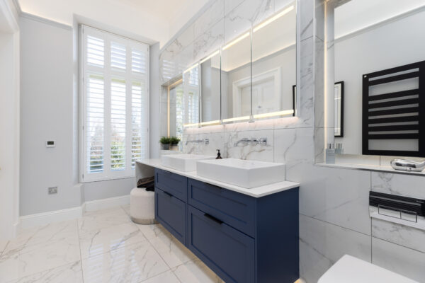 modern ensuite bathroom featuring a two-drawer vanity unit and a large mirror cabinet with LED lighting.
