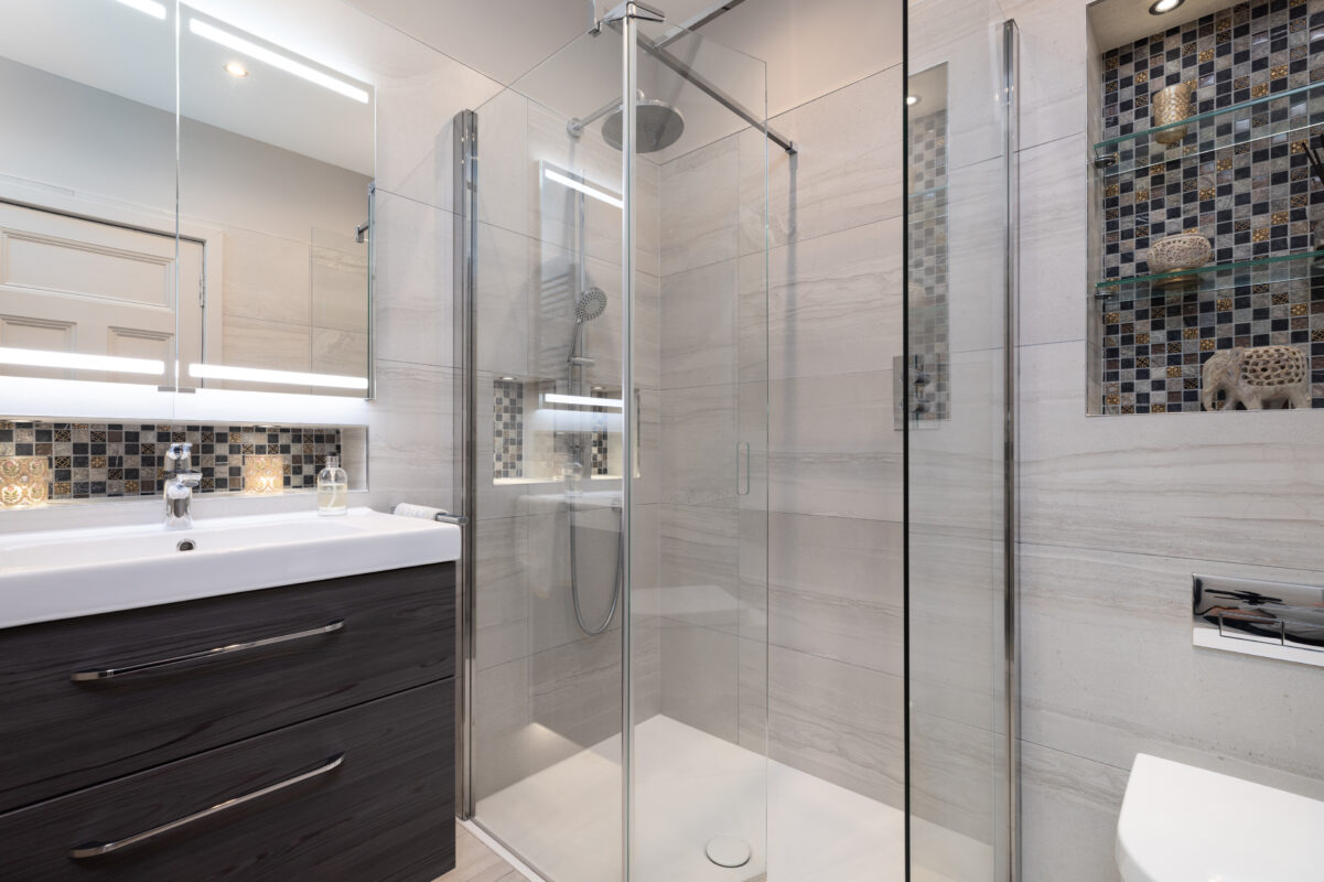 modern bathroom with a walk-in shower, floating wood vanity, mosaic tile recess for storage with lighting. A WC area with a recess shelve above as part of a whole home renovation in Edinburgh.