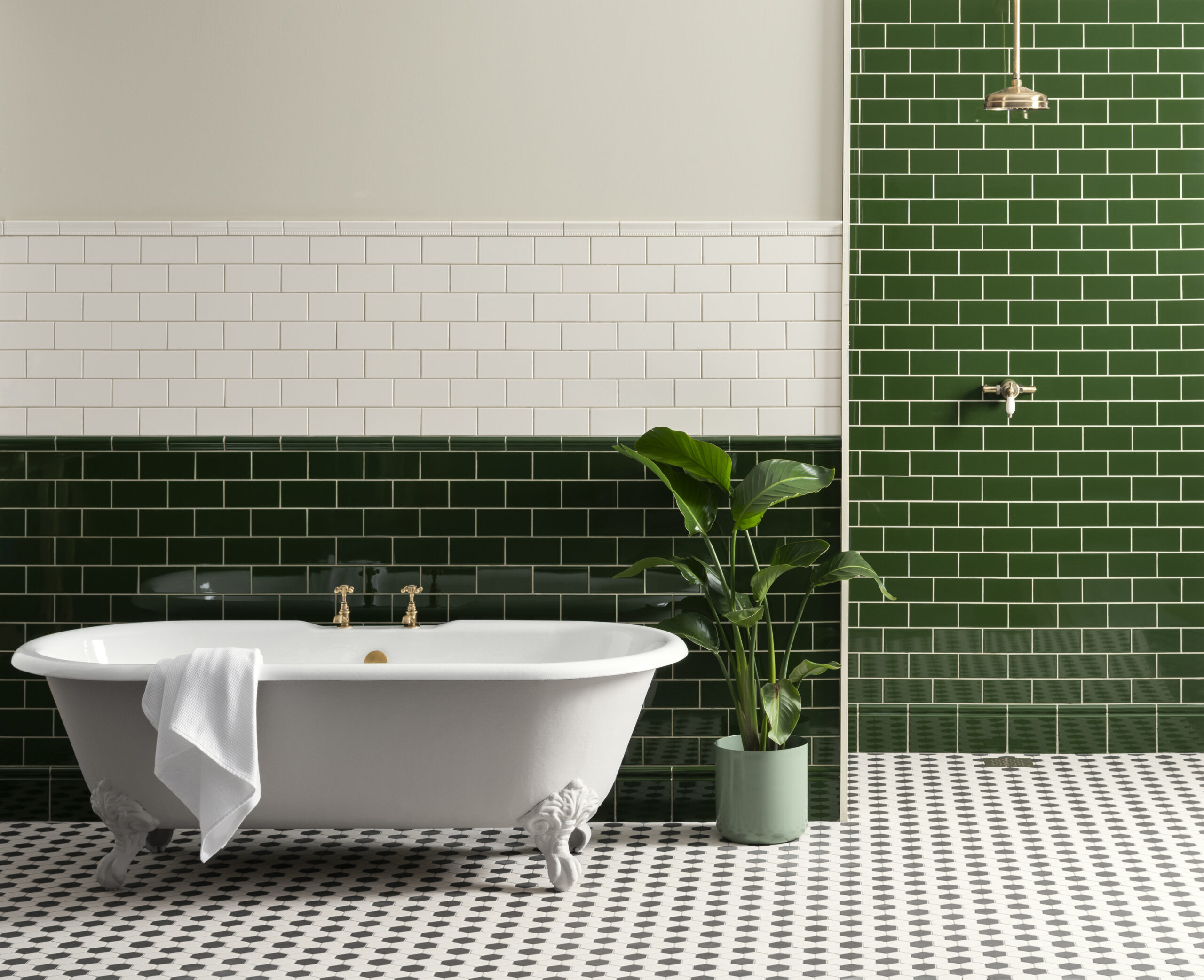 A free-standing clawfoot bath in white complements a classic-style bathroom. The space is fully tiled with green and white Edwardian tiles for a vintage look.