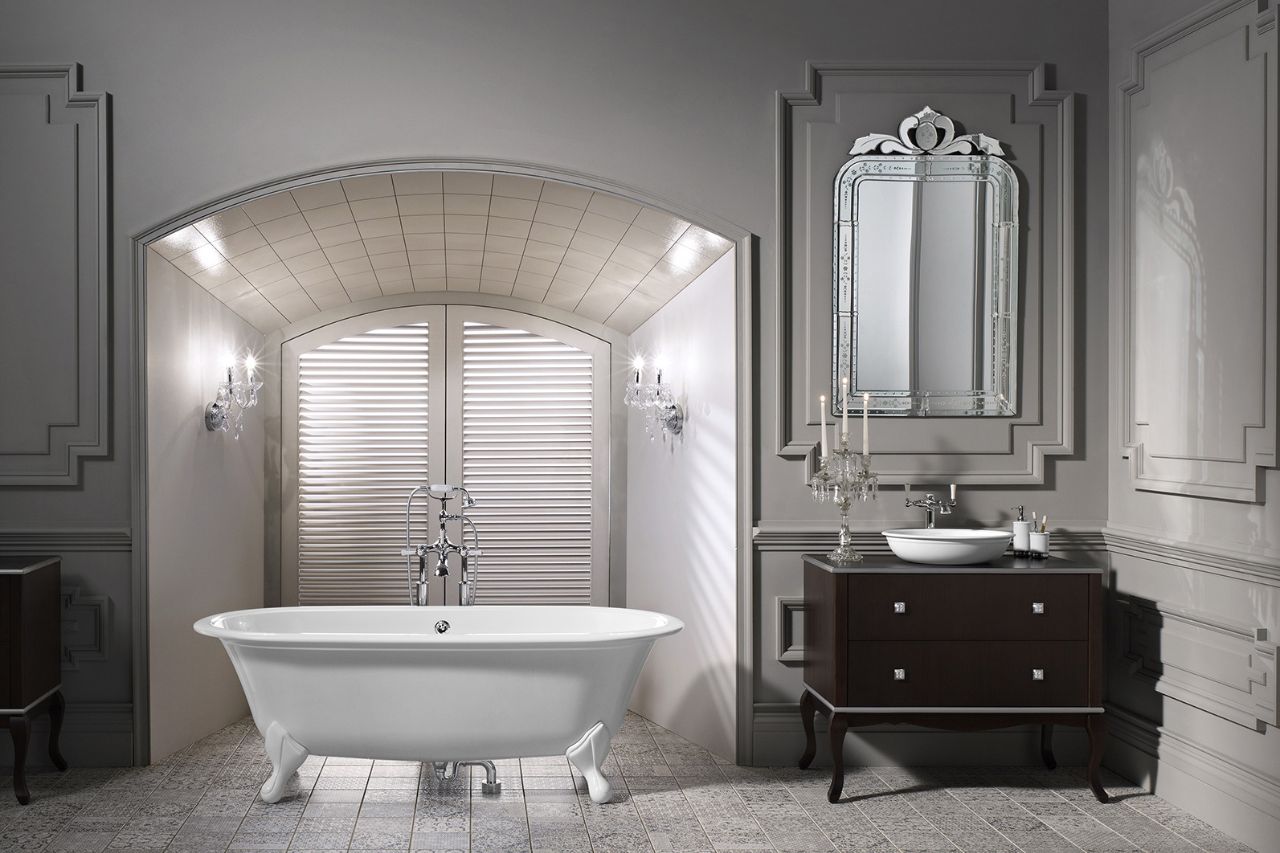 A classic bathroom features a free-standing white bath and a floor-mounted mixer, complemented by wood panelling in an off-whiteere is a vanity unit complete with a uniquely designed mirror. hue. At one end of the room, th