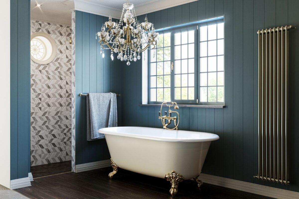 A stunning traditional bathroom with a chandelier that adds an elegant touch. The space also features a large freestanding bath and heated towel rails. The fixtures, clawfoot bath, heated towel rails, mixer tap, and chandelier, come in a brushed brass finish.