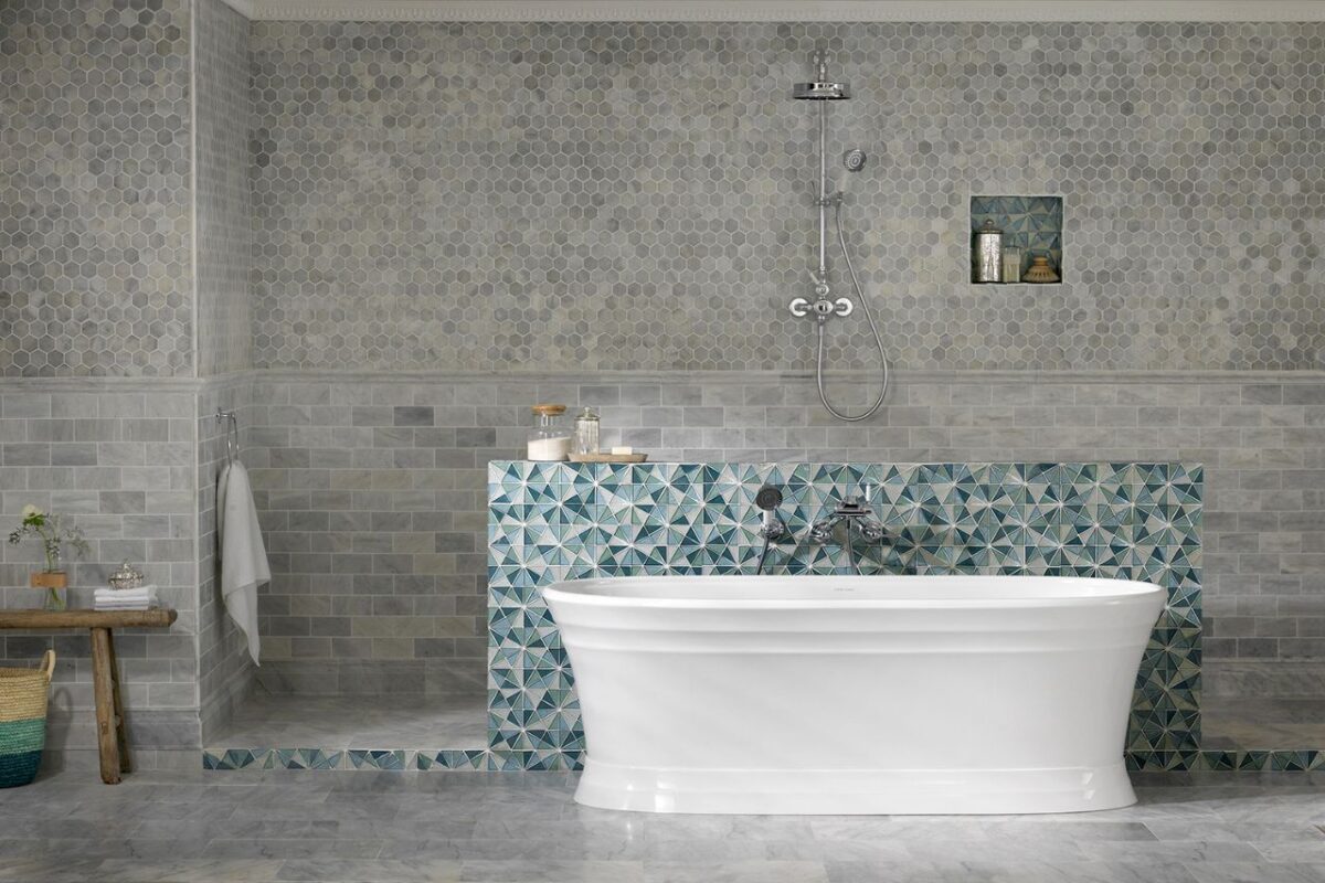 A very large bathroom with a traditional style. The space features a classic overhead shower with natural-coloured tiling. All fixtures come in a chrome finish for a consistent colour scheme. The area includes bathroom accessories with a nicely curved recess in the shower space.