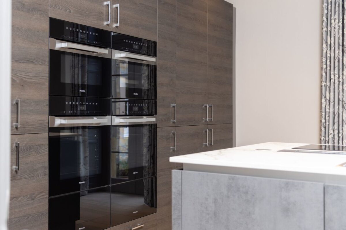 Kirthen cabinetry features an integrated appliance and a Miele oven. An island and a worktop are also displayed.