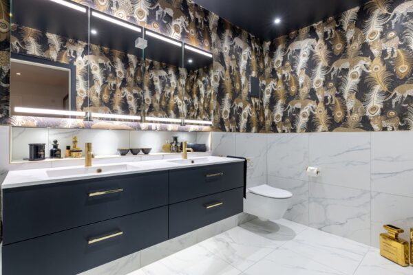 A large master ensuite bathroom with a dual vanity unit and basin. Above the vanity is an illuminated mirror cabinet. And a wall-mounted WC is also fitted to complete the space.