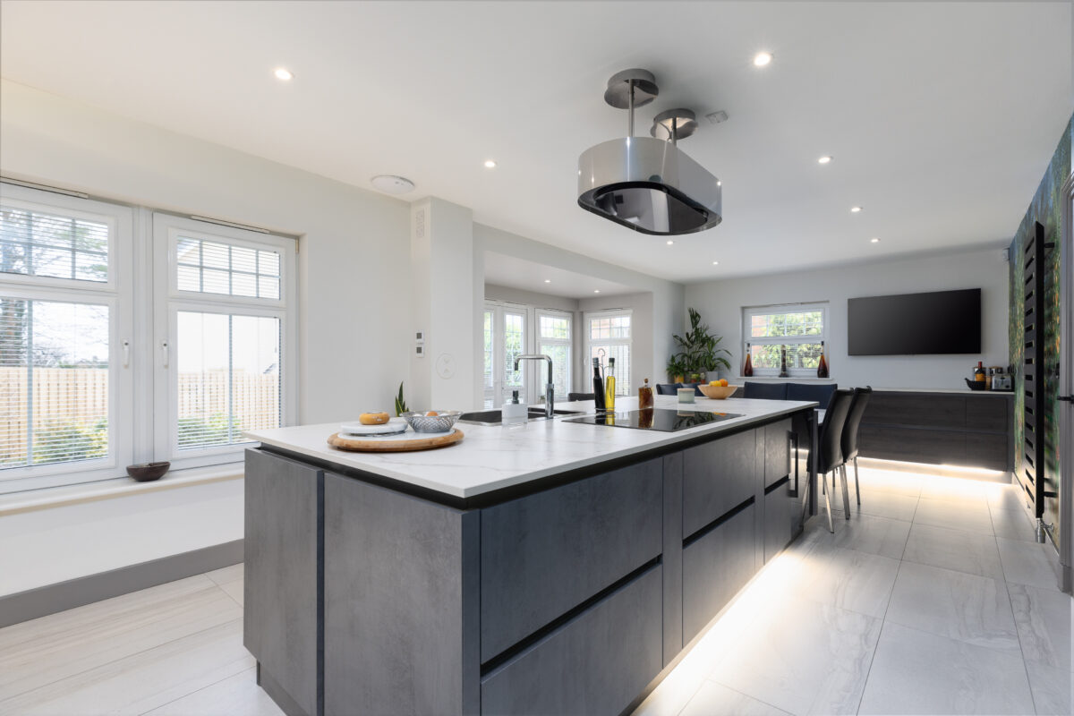 A newly renovated kitchen featuring a kitchen island and a dining area. The floor is fully tiled, and there is wallpaper on one side of the wall. The kitchen is part of an entire home renovation in Edinburgh.