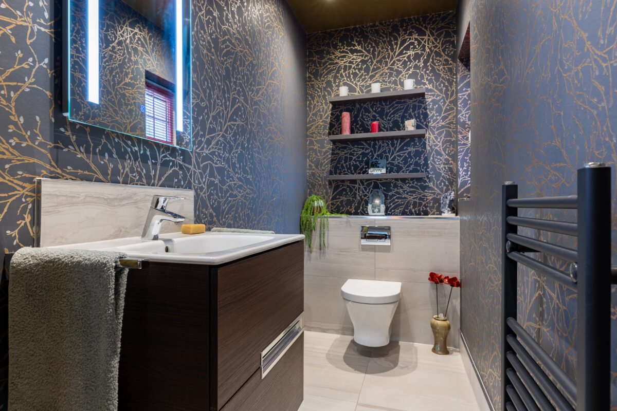 A cloakroom installation featuring floating shelves, a vanity unit, LED mirror, WC, and a heated towel rail in matte black. This room is a part of an entire home renovation in Edinburgh