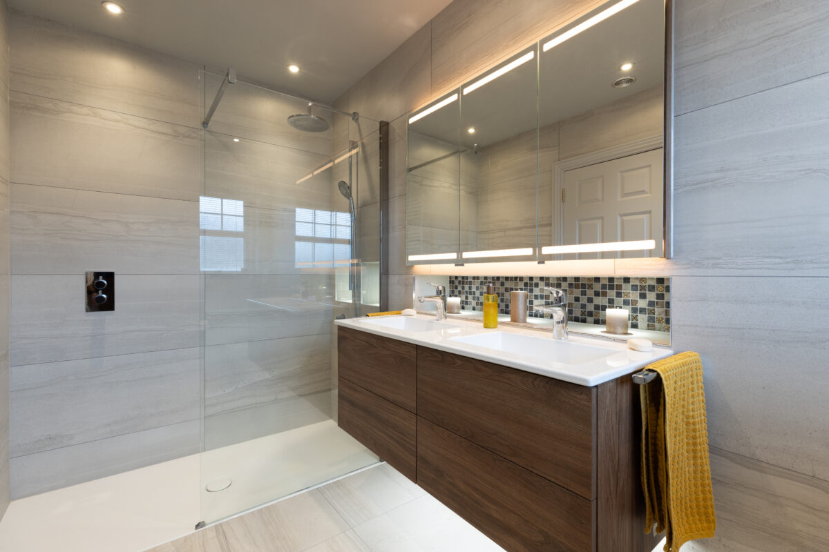 A large walk-in shower complemented by a four-drawer vanity with a dual basin. Above the basin, there is a three-door mirror cabinet and a recess with mosaic tiles. This is an ensuite as part of a full house renovation in Edinburgh.