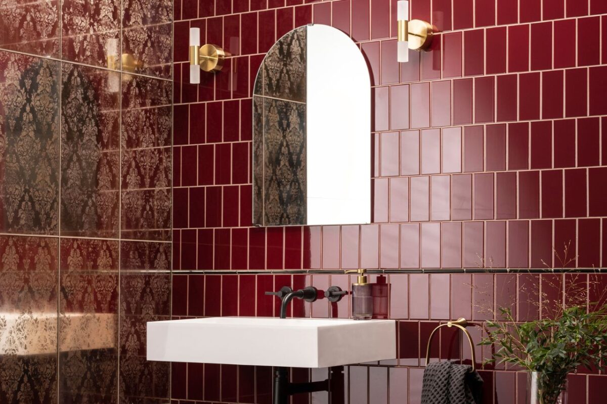 A spacious vanity area with a glass tiled splashback, a large mirror, a wash basin, and a mounted mixer.