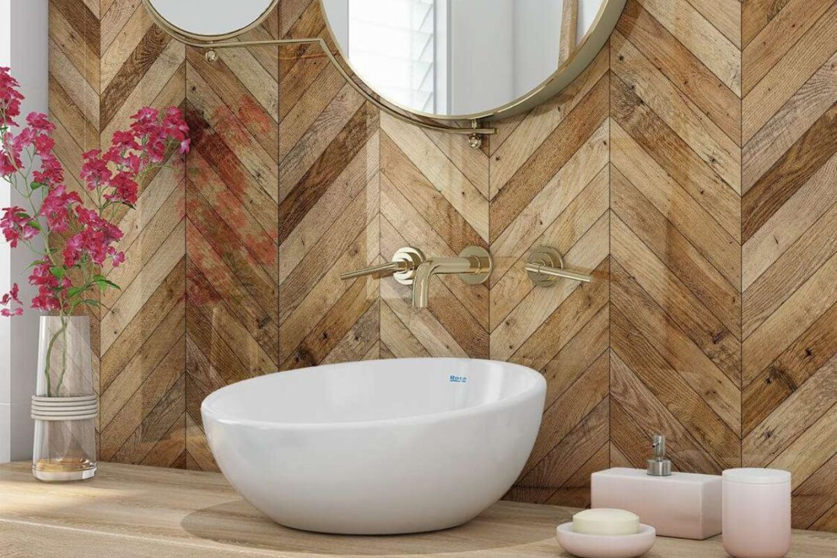 A wood-style splashback with a washbasin and brushed brass wall-mounted fixtures.