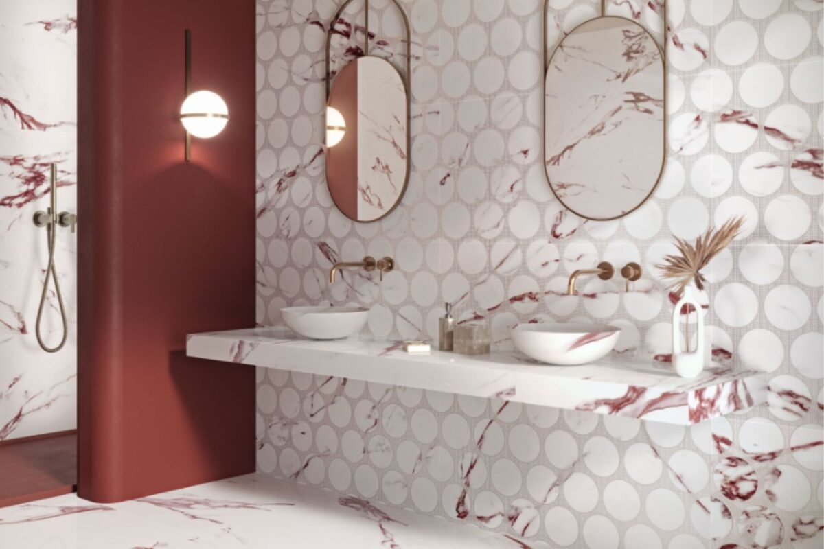 A spacious, modern-style bathroom with a geometric splashback and brushed brass fixtures.