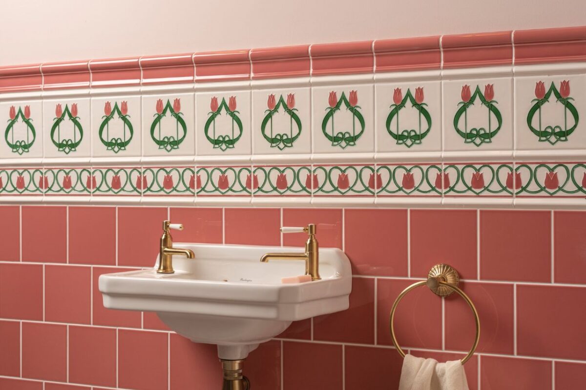 A contemporary subway-style pink splashback withtures in brushed brass. a basin and fix