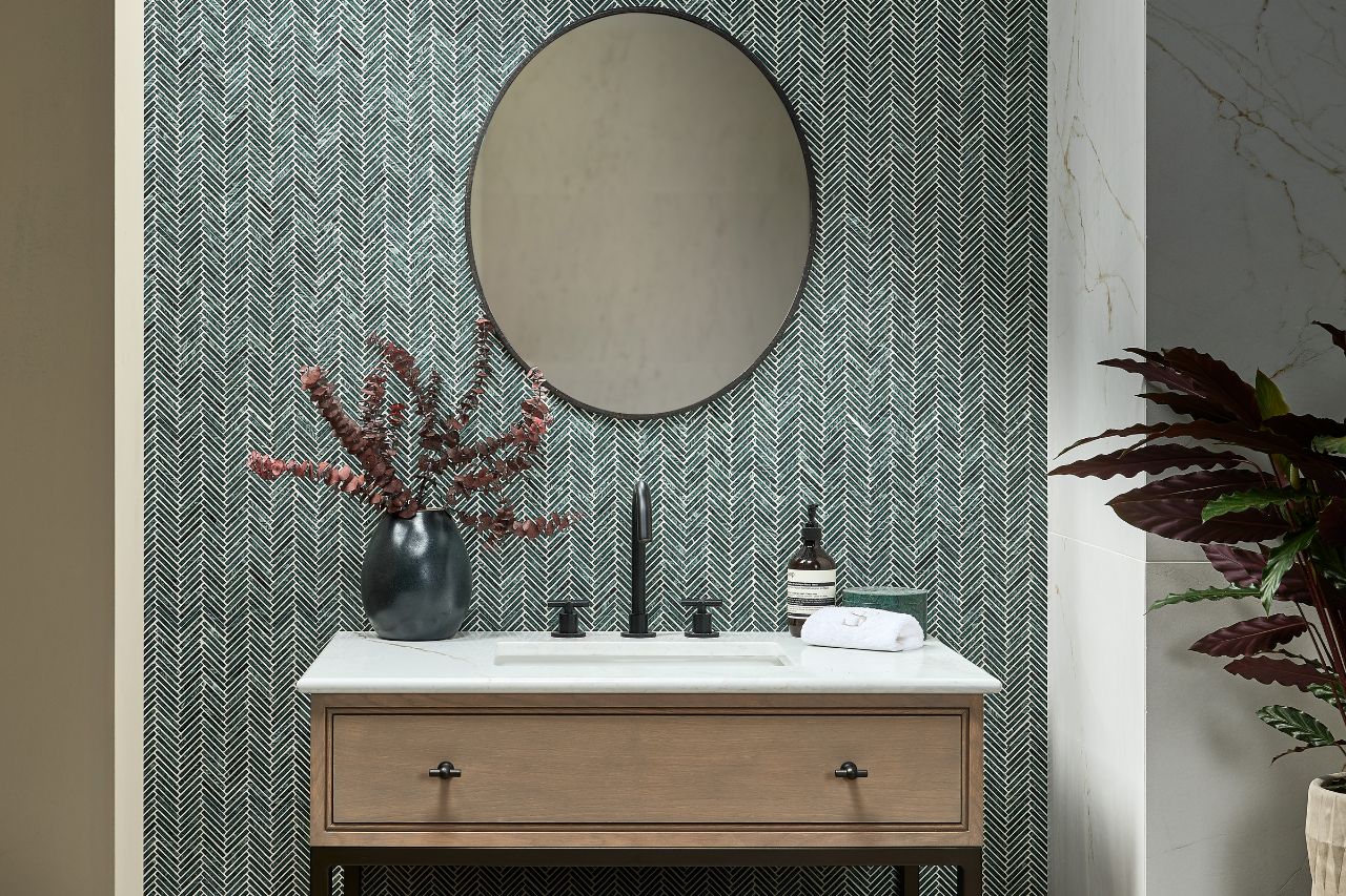 A mosaic-style splashback with an oval mirror and a large vanity unit.