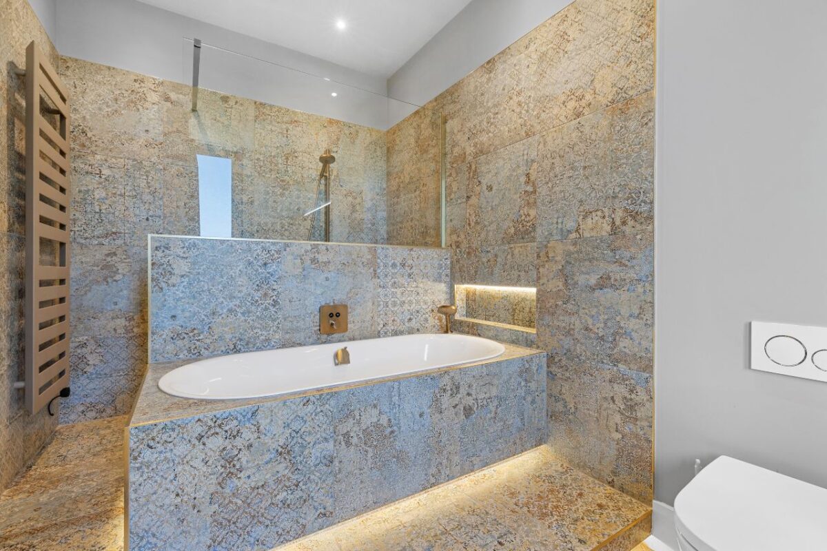 Fully tiled built-in bath and a shower wet room with a towel rail. The bathroom also features a recess with a built-in light.