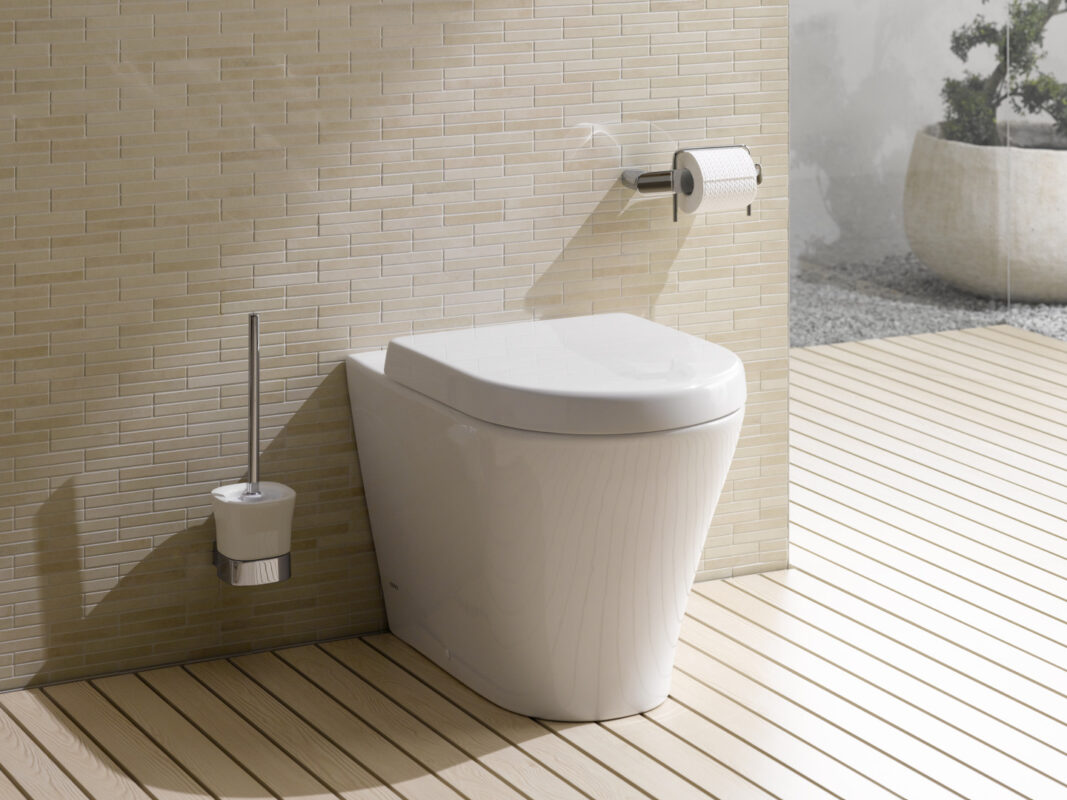 The Rimless toilet from TOTO, finished in white, is installed in a modern bathroom with toilet accessories.