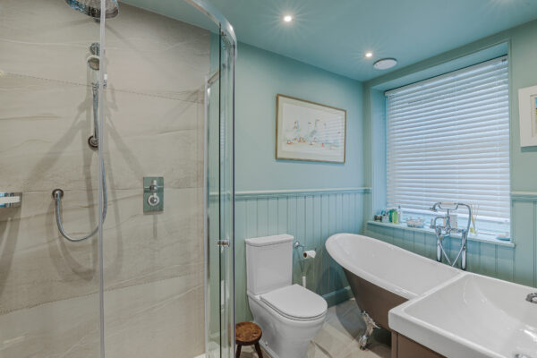 A beautiful downstairs bathroom renovation in Perth, which includes a stylish grey bath, a shower area, a sleek vanity, and a WC.