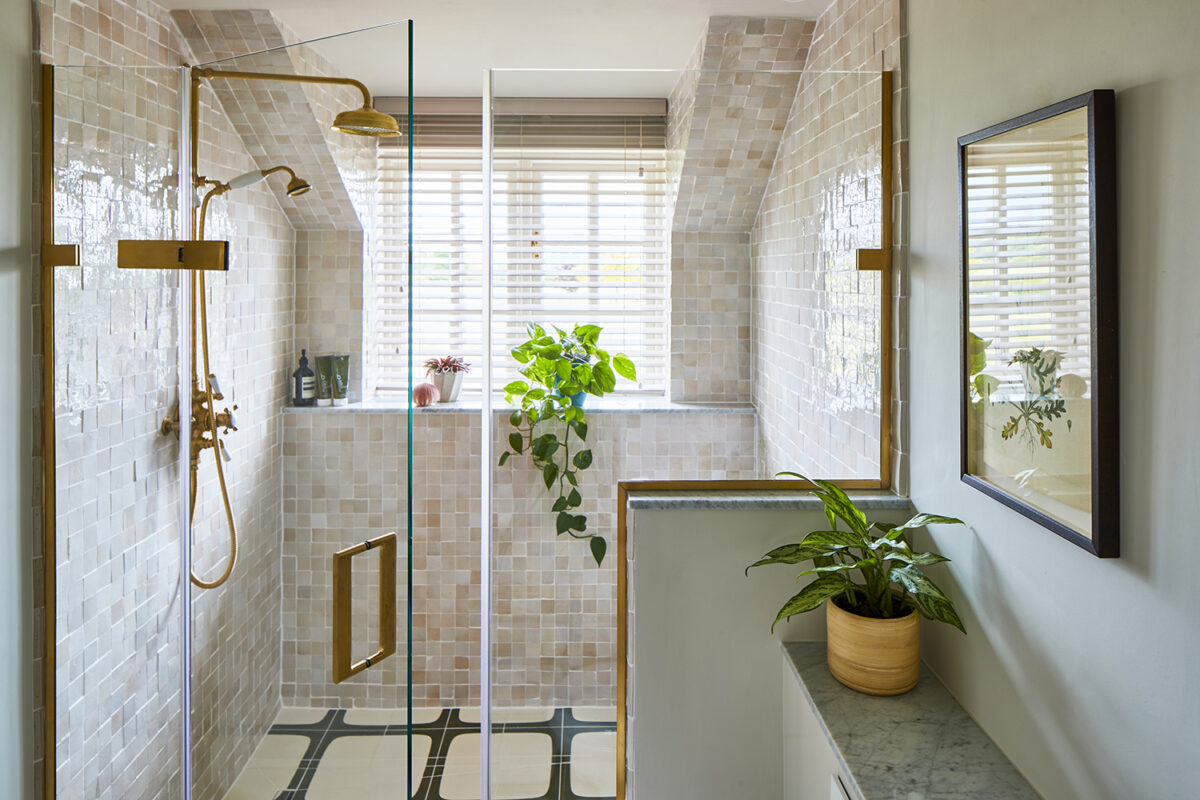A luxury bathroom with a large walk-in shower featuring brushed gold fixtures and a bespoke shower screen.