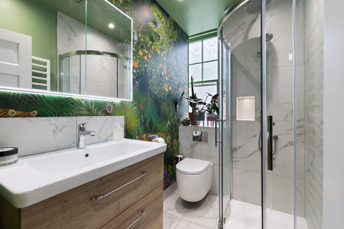 Compact shower room with wall-hung toilet, floating vanity unit, wallpaper feature wall, and glass shower enclosure in a modern small bathroom.